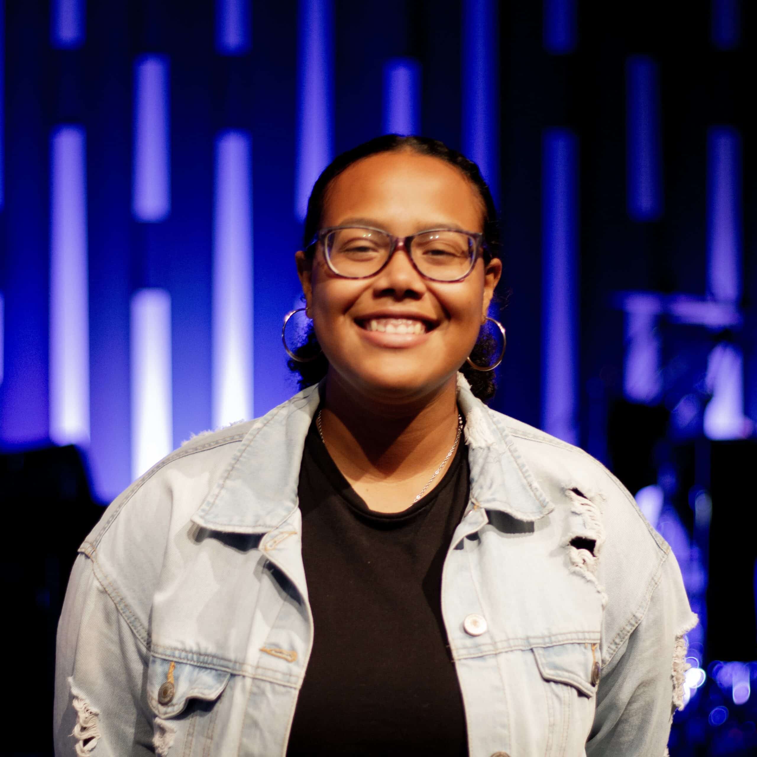 A woman wearing glasses and a denim jacket.