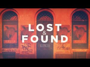 A building with arched windows and graffiti, featuring posters of a missing sheep and large text reading "LOST & FOUND LUKE 15".